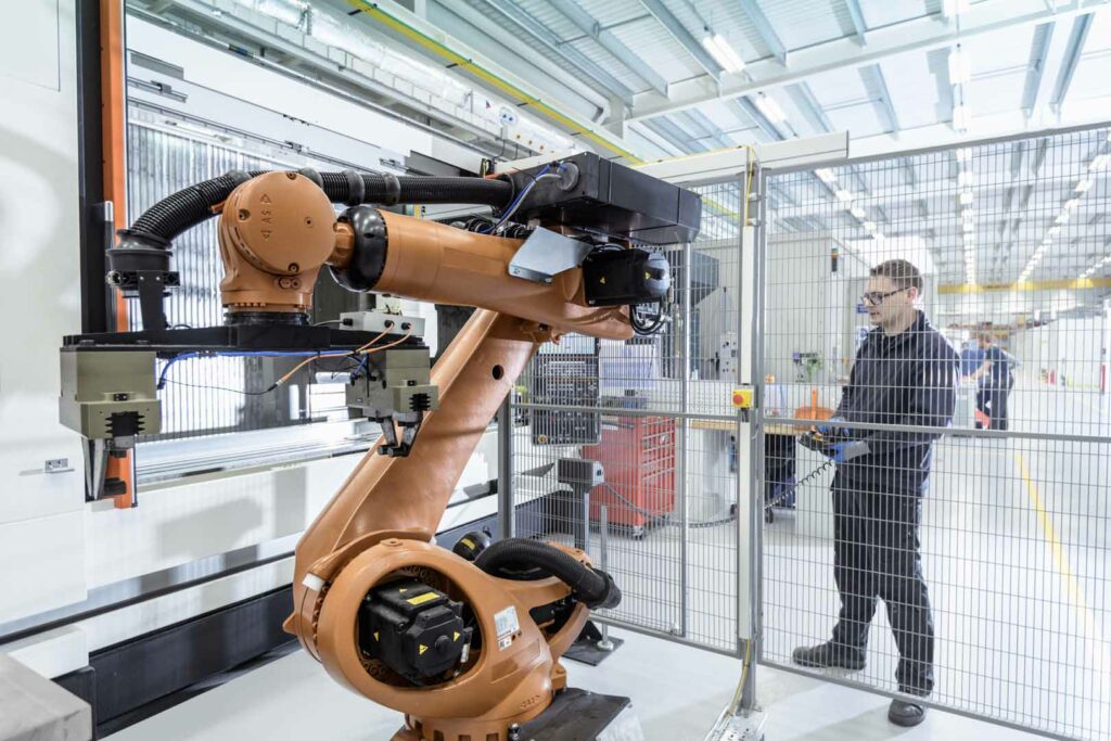 Robotics engineer operating robot aided CNC machine in robotics research facility